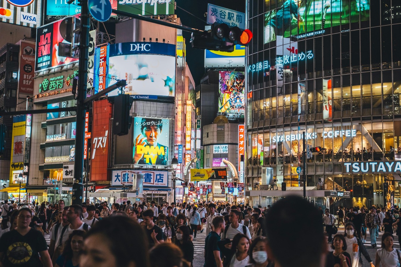 Crowds crossing a street among neon signs in Tokyo